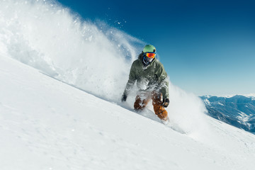 male snowboarder curved and brakes spraying loose deep snow on  freeride slope