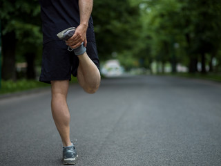 male runner warming up and stretching before morning training