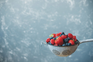 Mix of washed fresh juicy berries in colander. Background with copy space