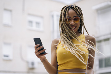 Afro-haired latin woman posing with mobile phone. - obrazy, fototapety, plakaty