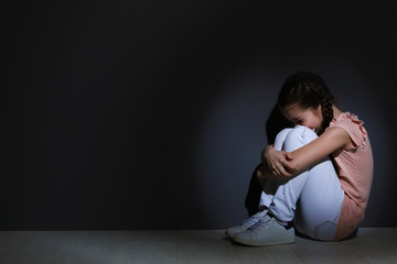 Depressed little girl sitting on floor indoors. Time to visit child psychologist
