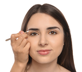 Young woman having eyebrow correction procedure on white background