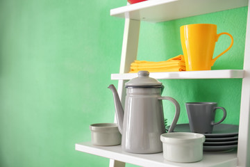 White shelving unit with ceramic dishware near color wall