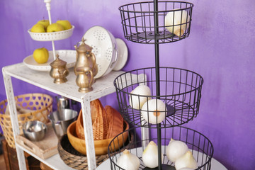 Metal stand and white storage stand with kitchenware near color wall