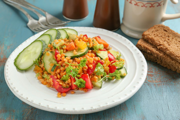 Plate with delicious lentils salad on wooden table