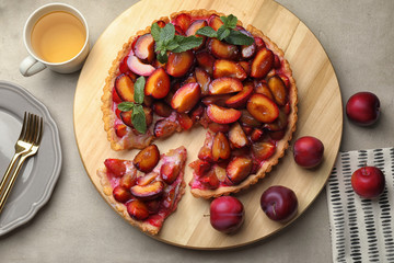 Sliced delicious pie with plums on wooden board