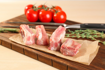 Wooden board with fresh raw ribs on table