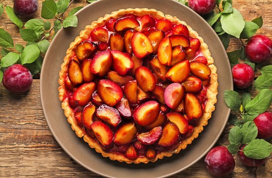 Delicious pie with plums on table