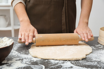 Woman rolling dough on table, closeup