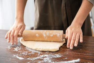 Woman rolling dough on table, closeup