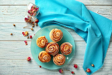Plate with apple roses from puff pastry on wooden table