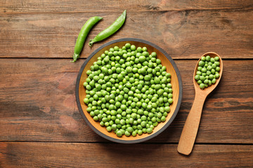 Flat lay composition with green peas on wooden background