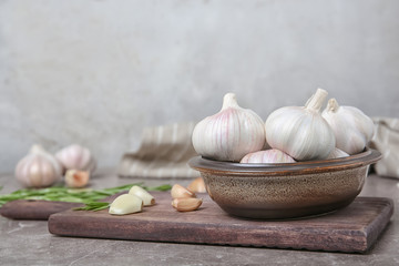 Bowl with ripe garlic bulbs on wooden board