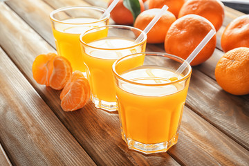 Glasses of tasty citrus juice on wooden table