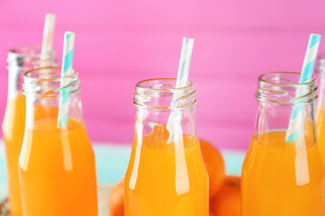 Bottles with fresh citrus juice on color background