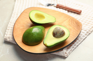 Wooden board with ripe avocados on table