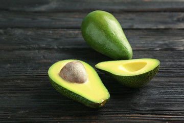 Tasty ripe green avocados on wooden background