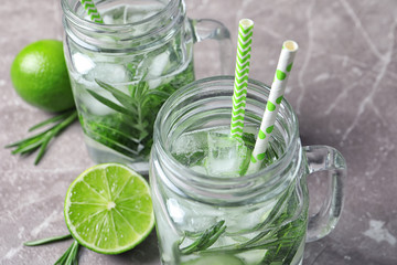 Natural lemonade with cucumber, lime and rosemary in mason jars on table, closeup