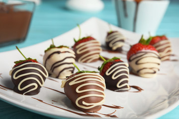 Plate with chocolate covered strawberries on table, closeup