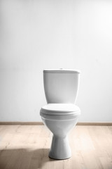 Fototapeta na wymiar New ceramic toilet bowl near light wall