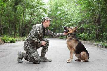 Man in military uniform with German shepherd dog, outdoors