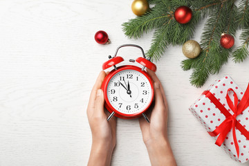 Woman holding retro alarm clock on table. Christmas countdown
