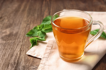 Cup with hot aromatic mint tea on wooden table
