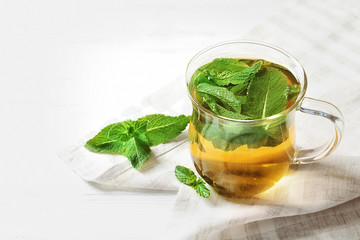 Cup with hot aromatic mint tea on table