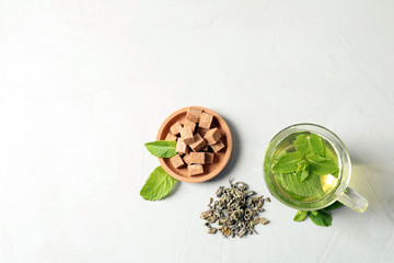 Cup with hot aromatic mint tea, dry leaves and sugar cubes on table, top view