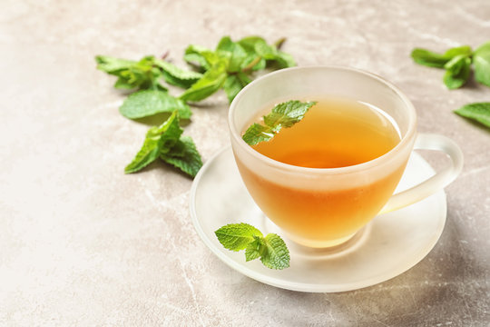 Cup with hot aromatic mint tea on table