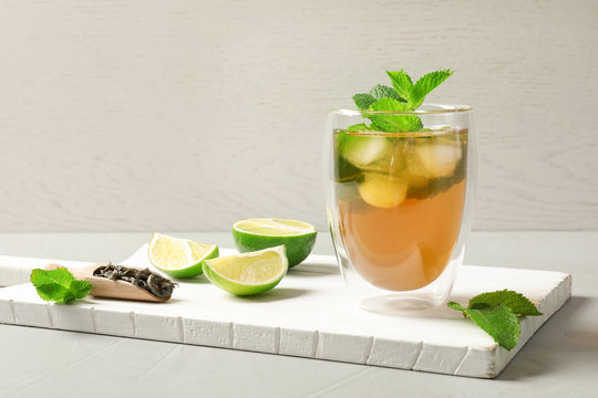 Glass with aromatic mint tea, fresh leaves and lime on wooden board