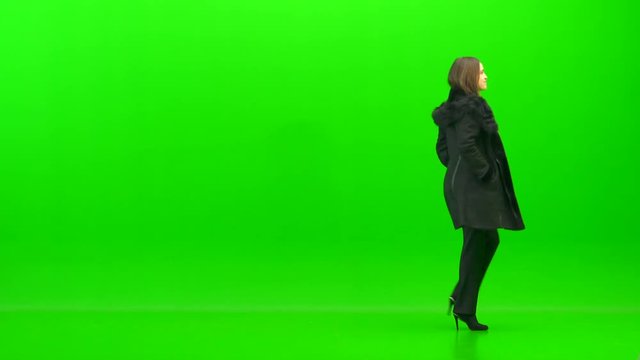 The woman walking with a coat on the green background