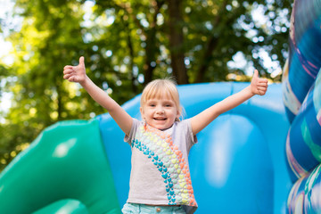happy excited girl having fun on inflatable attraction playground. 
