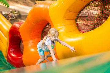 happy excited girl having fun on inflatable attraction playground. 
