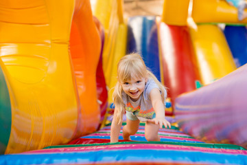 happy excited girl having fun on inflatable attraction playground. 