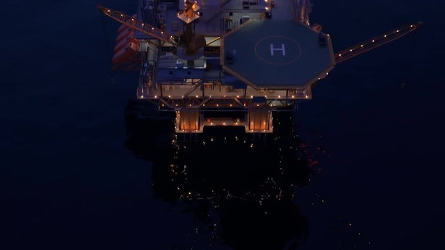 Illuminated offshore platform or oil rig in the open sea during night.