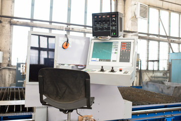 Modern equipped workplace of factory machine operator with computer monitor and chair at manufacturing plant