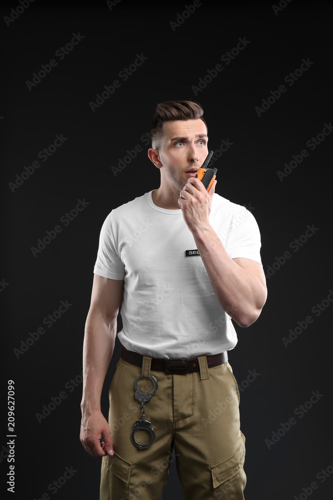 Wall mural Male security guard using portable radio transmitter on dark background