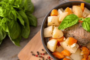 Bowl with tasty meat and potatoes on table