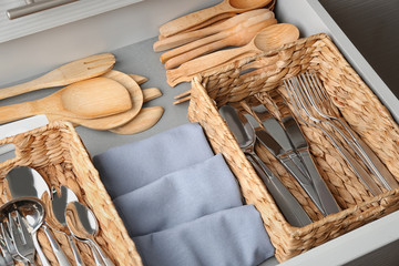 Set of cutlery and wooden utensils in opened kitchen drawer