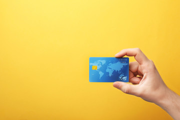 Young man holding credit card on color background