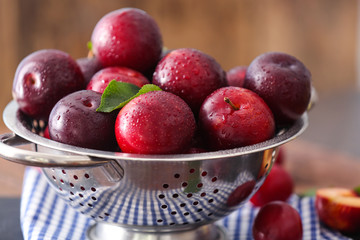 Naklejka na ściany i meble Colander with ripe juicy plums on table