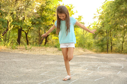 Cute little girl playing hopscotch, outdoors