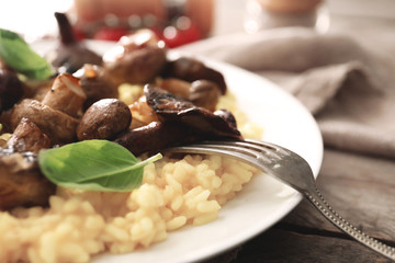 Plate with tasty risotto and mushrooms on table, closeup