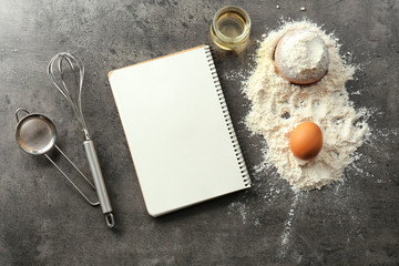 Notebook and products for making bread on grey background