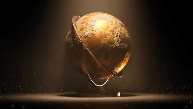Golden globe trophy, award or spherical model of earth spinning in a light beam.