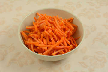 Pre-cut shredded raw carrots in white bowl as ingredient in salad or for cooking or for healthy dog treats