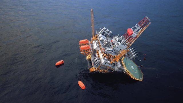 Collapsed offshore oil platform. Floating lifeboats in the sea. Oil Spill.