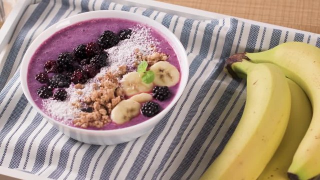 Healthy breakfast bowl: blueberry smoothie with banana, cococnut and blackberries.