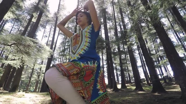 Attractive young woman in beautiful forest dances Indian style. 360 rotating shot, low angle